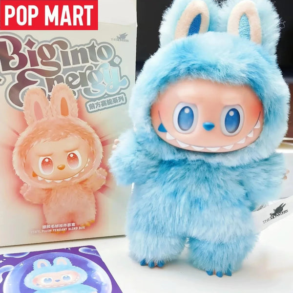 A fluffy blue Labubu plush doll with large ears and a smiling face is displayed next to its packaging.