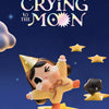 A yellow collectible figurine of a crying baby with dark hair and a bow, surrounded by gold stars against a dark blue backgro