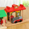 A wooden train track accessory set featuring a red house structure and a small red train model.