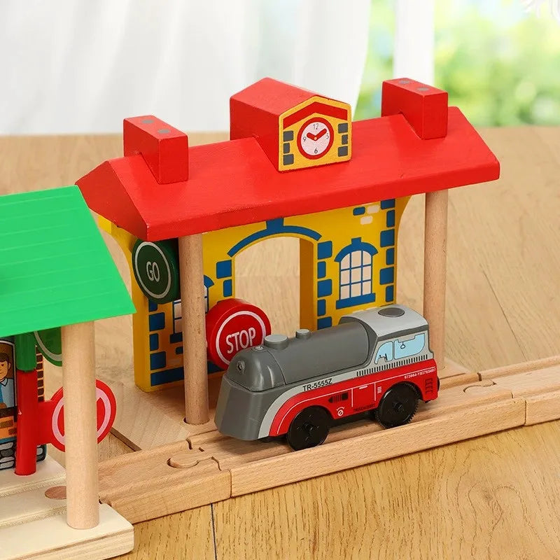 A wooden train track accessory set featuring a red house structure and a small red train model.
