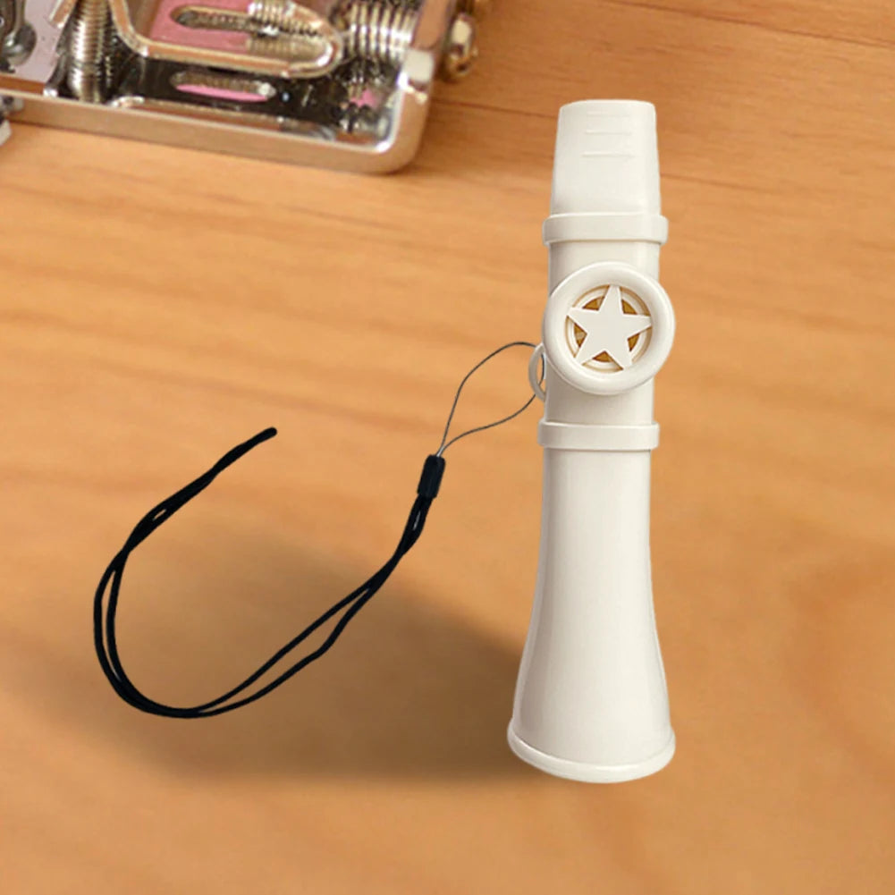 A white portable kazoo flute with a star-shaped mouthpiece and black lanyard resting on a wooden surface.