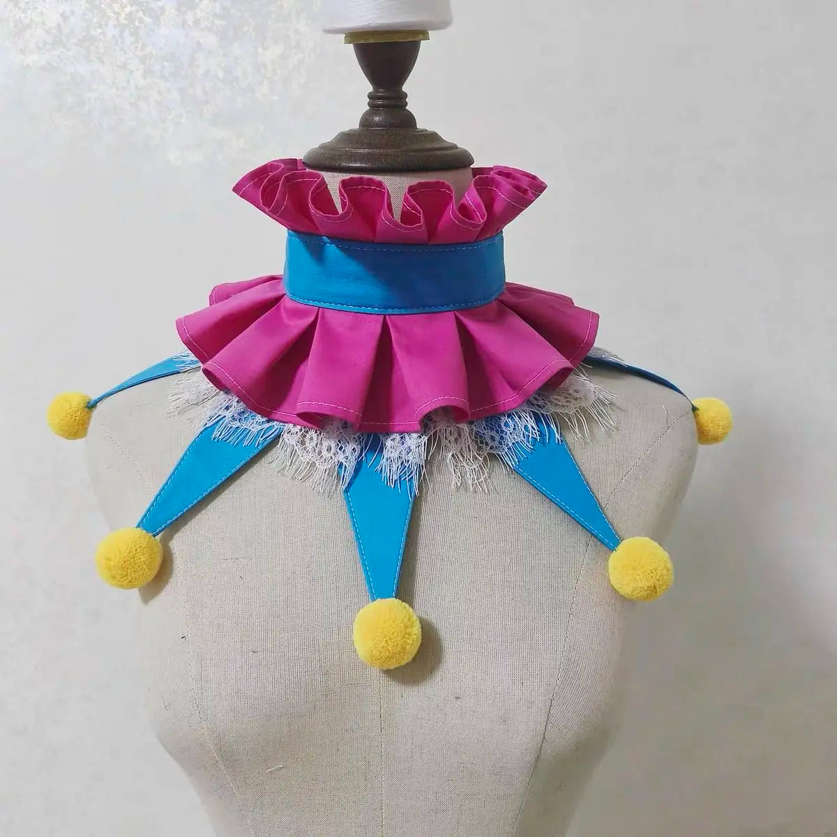 Handmade colorful clown ruff collar featuring pink and blue ruffles and yellow pom-poms