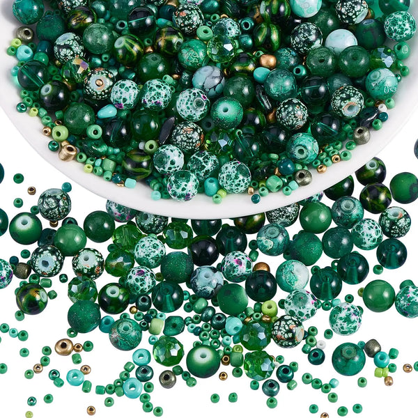 A close-up view of mixed size green glass seed beads in various shades and textures.