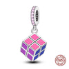 A silver charm shaped like a Rubik's cube with pink and purple facets, featuring a decorative top.