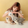 Three realistic seal plush toys in white, brown, and gray are displayed on a white surface.