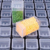A clear plastic storage box filled with yellow beads or craft items, set among many transparent compartments.