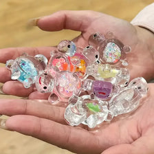 A hand holds a collection of glow-in-the-dark mini sea turtle figurines for craft projects.