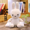 A white Miffy plush toy with long ears is shown standing on a wooden surface.