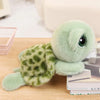 A soft, light green plush sea turtle stuffed animal resting on a wooden surface next to a stack of books.