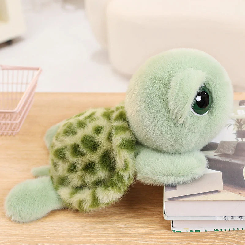 A soft, light green plush sea turtle stuffed animal resting on a wooden surface next to a stack of books.