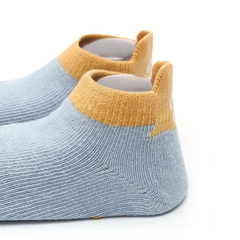A pair of light blue knitted socks with tan cuff and non-slip grips shown from the side.