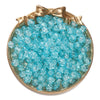 A round dish filled with clear blue glass crackle beads tied with a gold bow for jewelry making