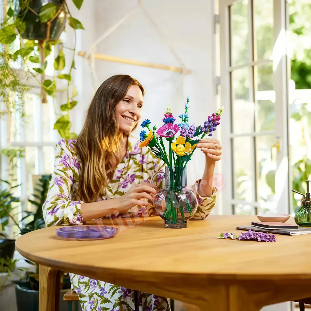 A woman holds a bouquet of colorful flowers in a glass vase on a wooden table.