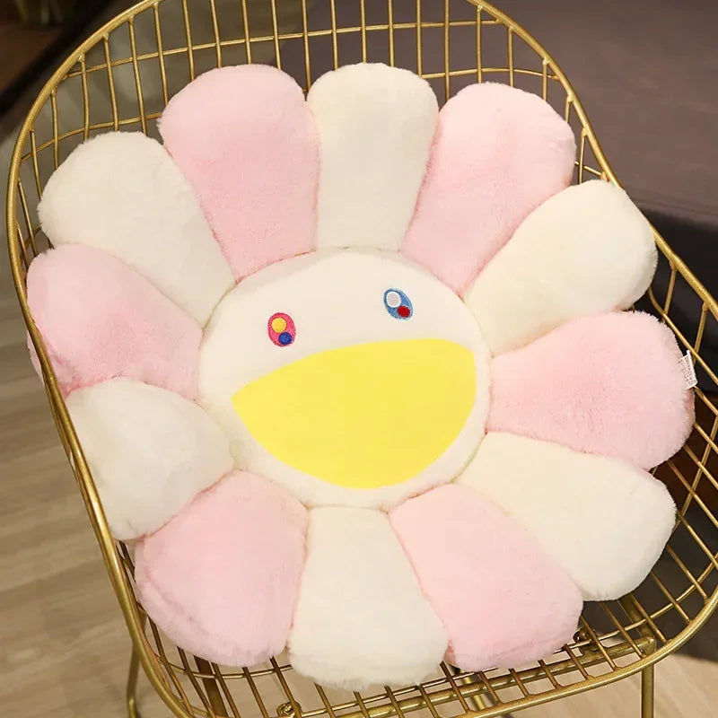 A large sunflower plush cushion with pink and white petals is displayed in a gold wire basket.
