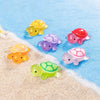 A collection of glow in the dark mini turtle collectible figurines in various colors scattered on a blue, snowy surface.