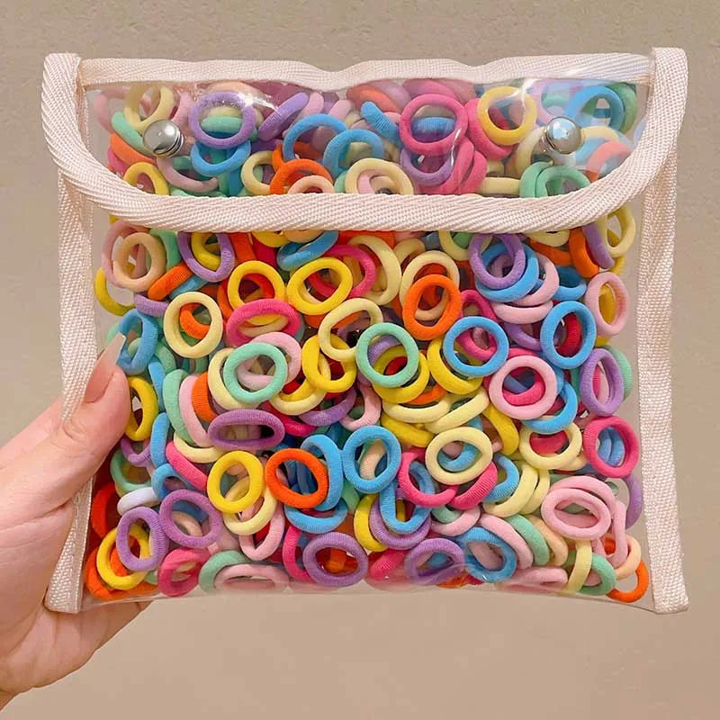A clear plastic bag filled with a multi-pack of colorful nylon hair ties in various shades of pink, blue, yellow, and orange.