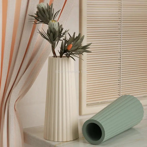 A vase holds dried foliage and an orange flower, next to a silicone mold for epoxy flowers.