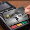 A close-up of a Berserk anime card sticker placed on a credit card within a black electronic device.