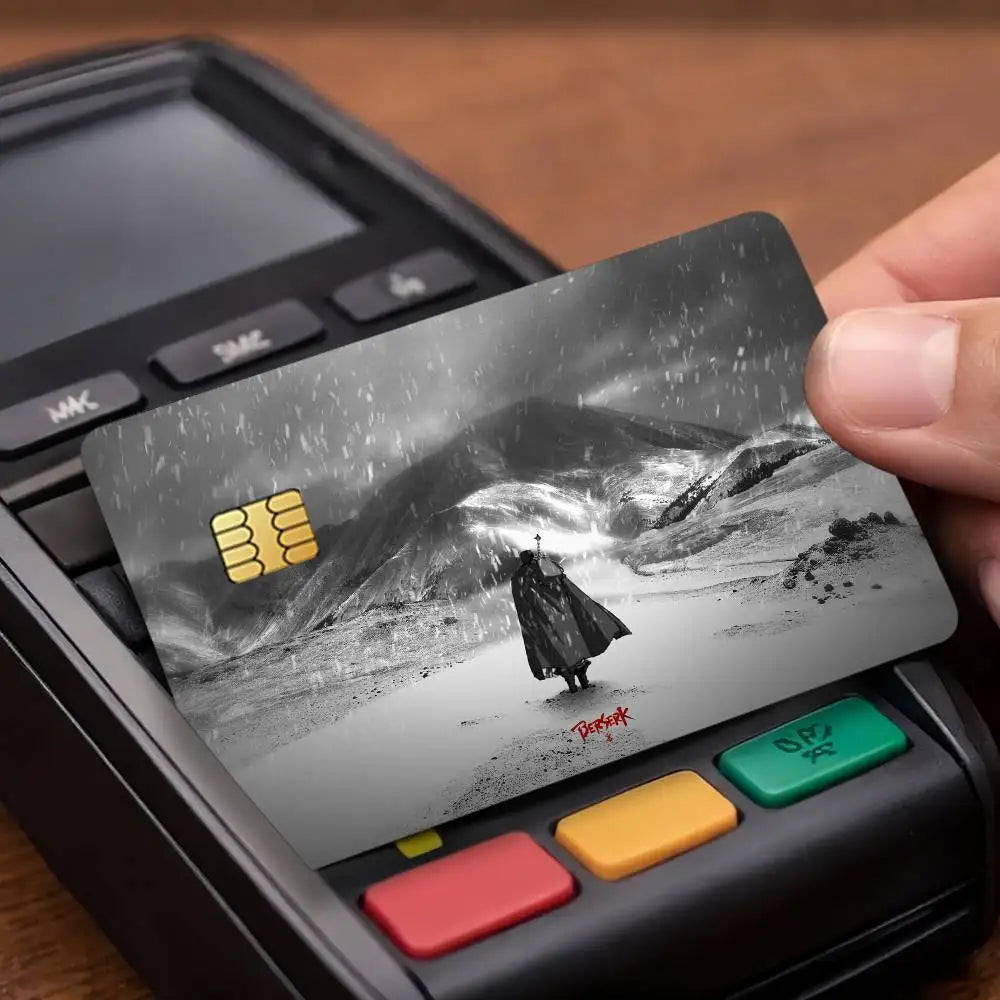 A close-up of a Berserk anime card sticker placed on a credit card within a black electronic device.