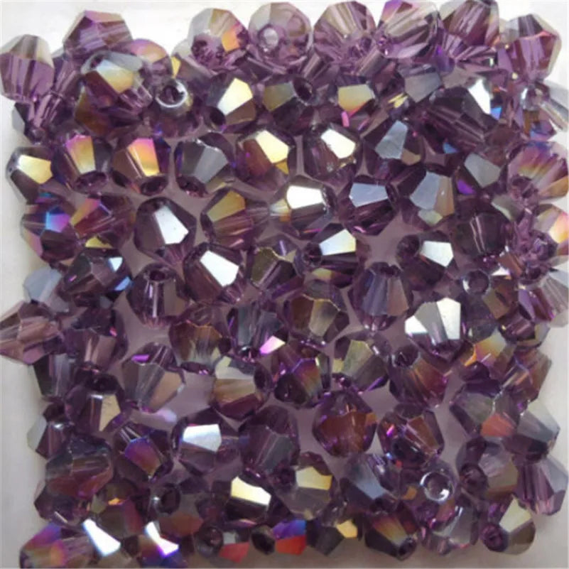 A close-up of faceted purple glass bicone beads used for jewelry making.