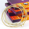 A coil of gold anti-rust coated acoustic guitar strings is displayed next to several boxes.