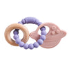 A purple silicone planet teether with a wooden ring and a pink silicone face shape for babies