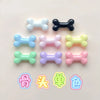 A collection of small resin bone charms in various pastel colors including blue, pink, yellow, and black.