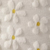 White faux fur pillow covers featuring embroidered yellow daisy designs on a textured fabric.