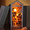 A DIY book nook kit featuring a wooden bookshelf insert with warm LED lighting and decorative elements.