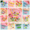 A collection of cute cartoon four-color ballpoint pens in various colors and designs arranged on a pink background.