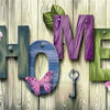 Wooden letters spelling HOME decorated with pink flowers and a key