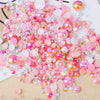 A pile of mixed resin rhinestone pearls in pink and gold finishes for crafts and nail art