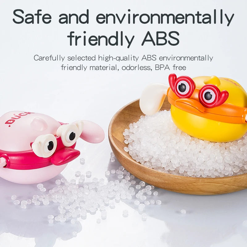 A yellow wind-up swimming bath toy animal is shown next to a pile of clear bath salts on a wooden surface.