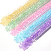 A collection of colorful glass beads in a rainbow gradient are displayed on a clear plastic strip.