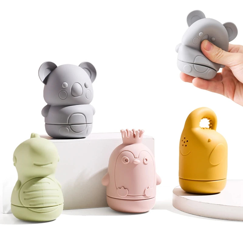 A hand holds a gray silicone animal bath toy next to other soft silicone animals.