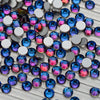 A collection of iridescent glass crystal flatback rhinestones in various shades of blue, purple, and pink.