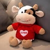 A red and white plush cow stuffed animal with a heart embroidered on its chest.