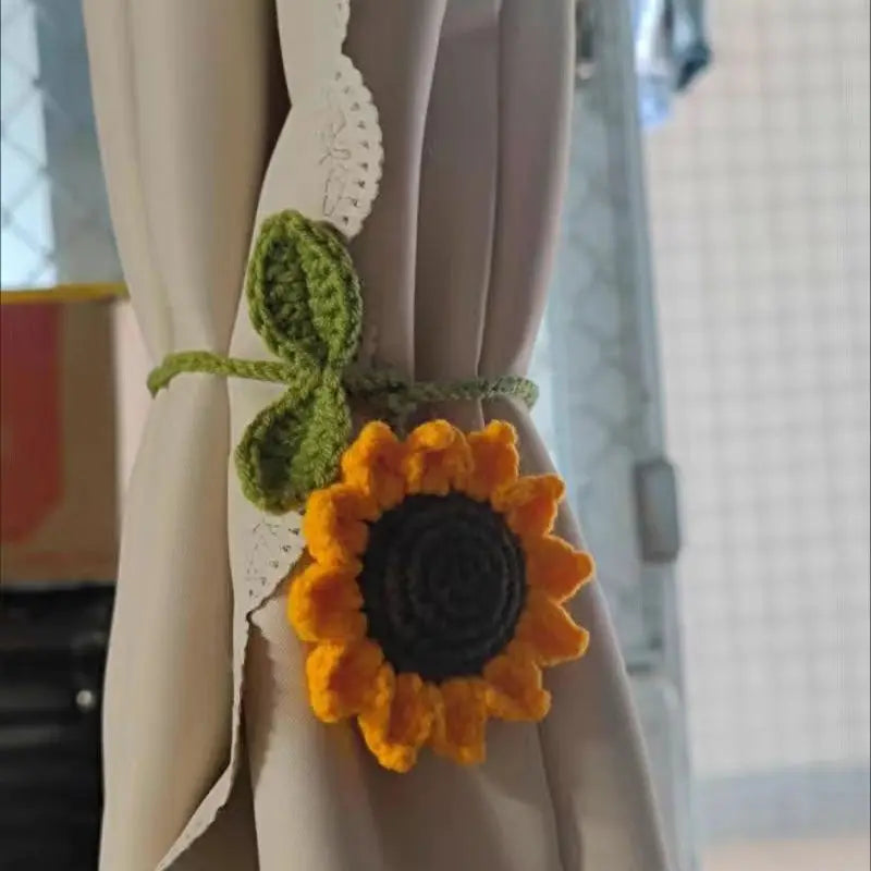 Handmade crochet sunflower charm attached to a white curtain fabric