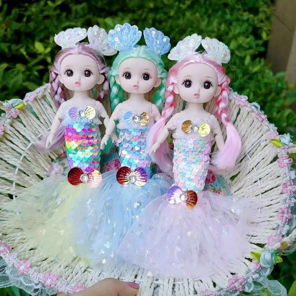 Three mermaid dolls with pink and blue hair and sequin dresses are displayed in a woven basket.