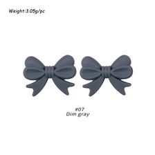 A pair of gray silicone bow tie beads used for jewelry making and craft projects.