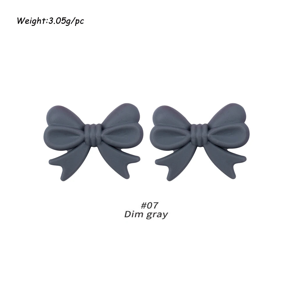A pair of gray silicone bow tie beads used for jewelry making and craft projects.