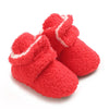 A pair of bright red, fuzzy baby winter boots with white trim.