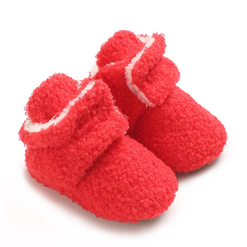 A pair of bright red, fuzzy baby winter boots with white trim.