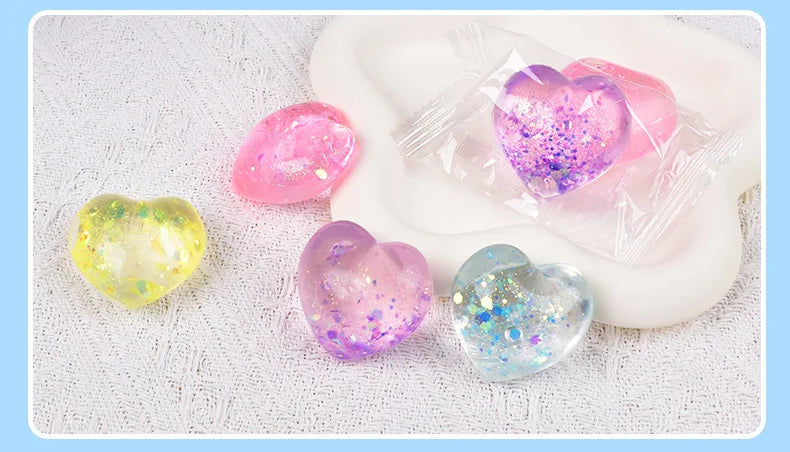 A collection of iridescent heart-shaped squishy toys in pink, yellow, and blue colors resting on a white surface.
