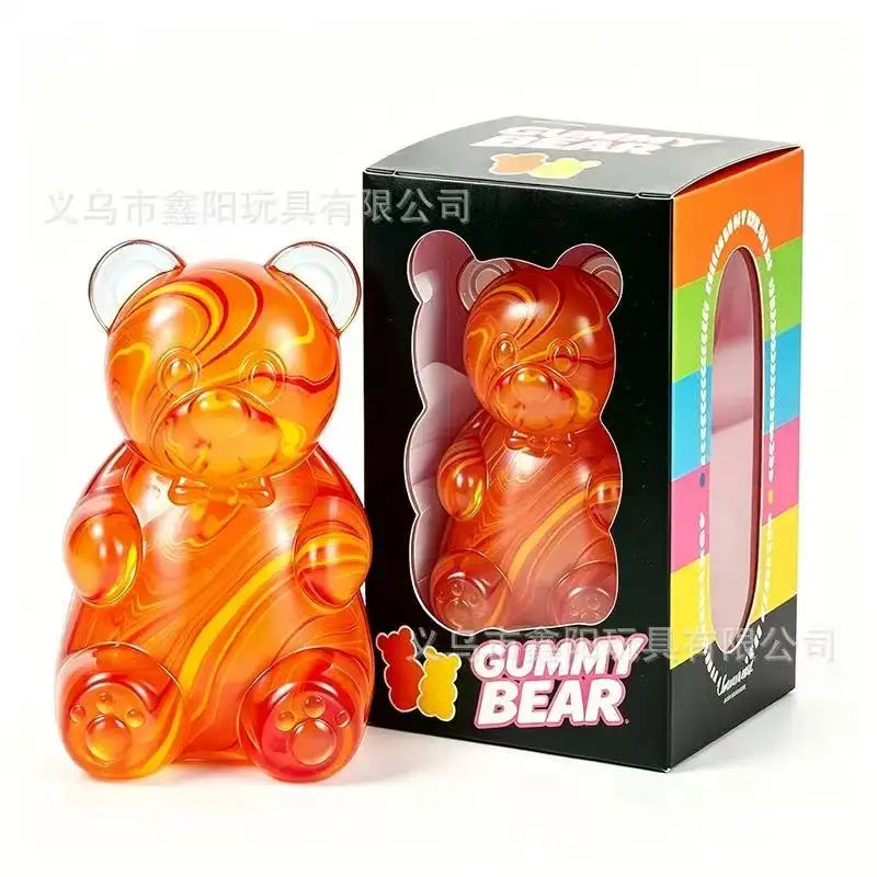 An orange gummy bear squeeze toy in a cardboard box with colorful stripes.