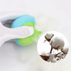 A hand is squeezing a bright blue and lime green sticky dodgeball vest for kids, with white fluff particles visible.