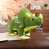 A green dinosaur plush toy with yellow accents sits on a brown leather couch.