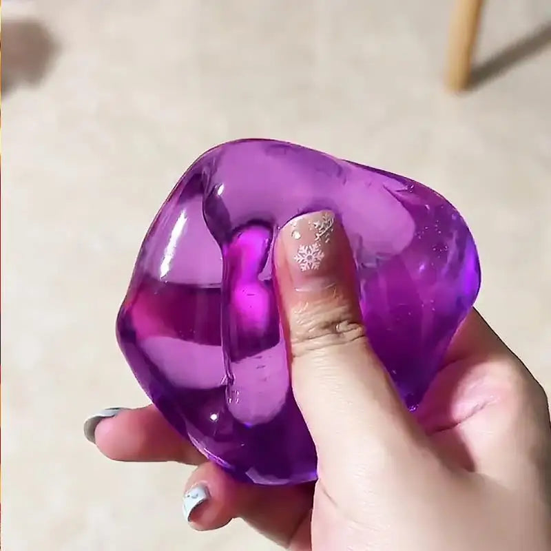 A hand holds a translucent purple slow rebound ice cube sensory fidget toy.