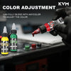 A hand adjusts a tattoo color using an ink dropper, with various colored inks and bottles visible on a dark surface.
