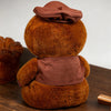 A brown sloth plush toy wearing a brown hat and vest, viewed from the back.